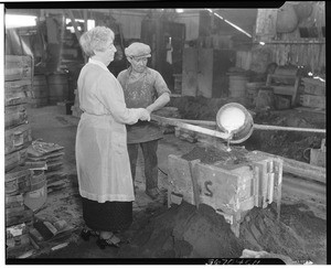 Mrs. A. S. C. Forbes pouring metal into a mold to create a bell, ca.1930
