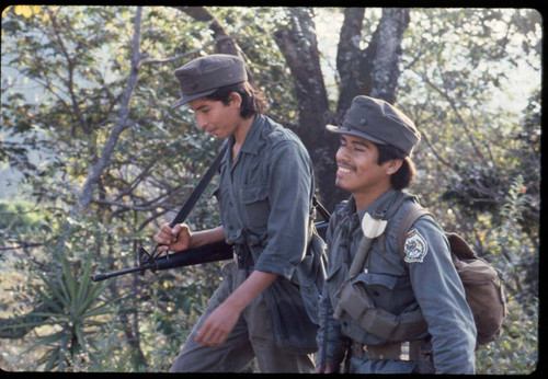 Two guerrilleros smiling and walking on a trail La Palma, 1983