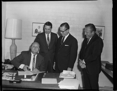 Men signing document in an office and stamping seal at bottom