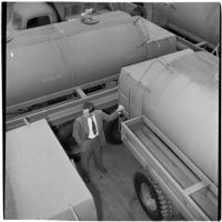 Man stands surrounded by gasoline trucks at the War Assets Administration's surplus truck and trailer sale, Port Hueneme, May 1946