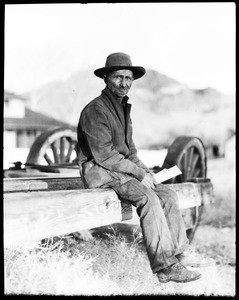 Man holding letters, sitting on a wagon frame