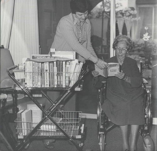 Margaret Magnuson bringing books to Mrs. Iva Elms, resident of Beverly Manor Laguna Hills