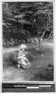 Japanese woman holding a teapot in a wooded area, Japan, ca. 1930-1950