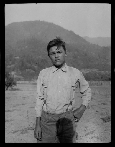 View of a boy, possibly Native American, standing in a field