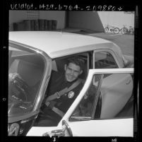 Police officer Paul Lembke showing safety [seat] belt installed in all police cars in Torrance, Calif., 1961