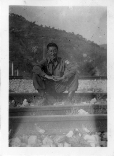[Man in military uniform sitting on railroad tracks]