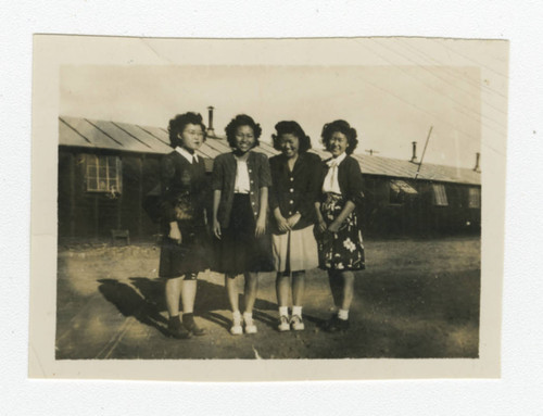 Young Nisei women standing outside barrack