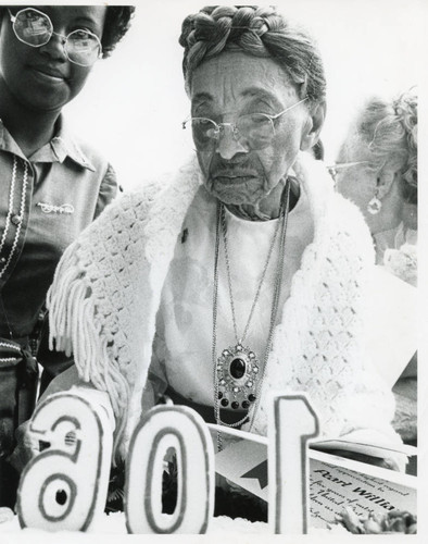 Pearl Williams admiring her 106th birthday cake during foster grandparents ceremony, 1975