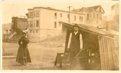 [Man and woman standing next to a street kitchen.]