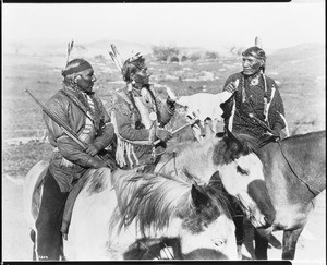 Portrait of three Indians of the Thundering Herd holding a cow skull, ca.1900