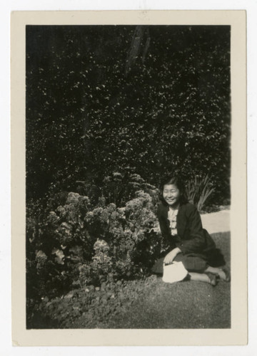 Woman sitting near bush