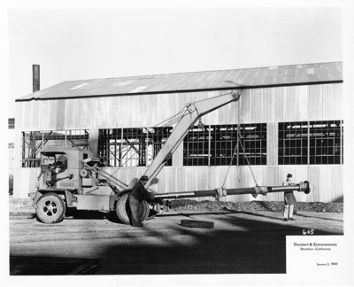Construction Equipment - Stockton: Crane holding a pipe, three unidentified men adjacent to crane, Guntert and Zimmerman Construction Co., 533 S. Aurora St