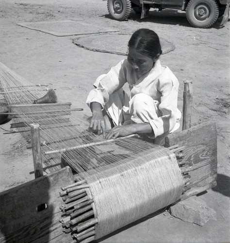 Woman weaving at a street-side loom