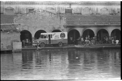 Boats, men and a truck by the river market, Cartagena Province, 1975