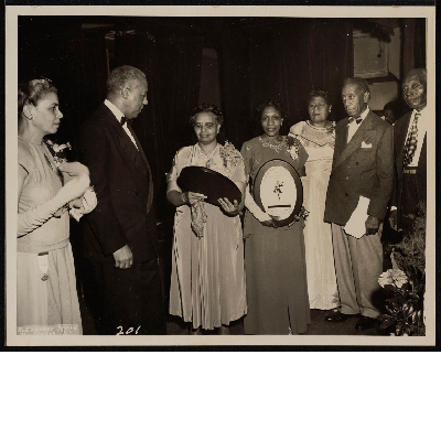 A. Philip Randolph standing next to winners of the Members of the Ladies Auxiliary to the Brotherhood of Sleeping Car Porters Meritorious Service Award winners