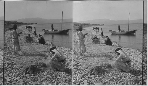 Fishermen mending nets at Jordan’s entrance to Sea of Galilee. Palestine