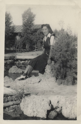 Young woman sits near a pond at Poston incarceration camp