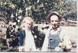 Little girl and older man in an apple orchard, about 1950