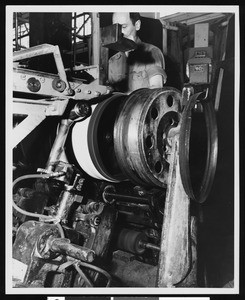 Factory worker standing behind a tire-production machine, ca.1930