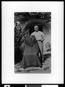 Portrait of John O. Forester holding a Mexican poncho once worn by grandfather Don Juan Forster of San Juan Capistrano, ca.1930