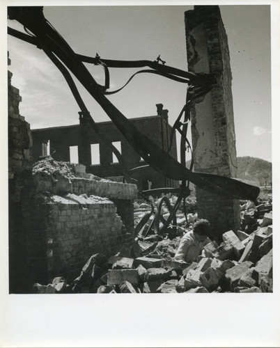 Woman working in the rubble among the twisted metal of a bombed-out building