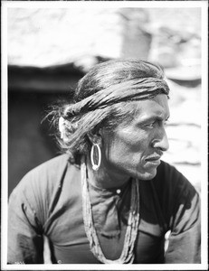 Portrait of Navajo Indian man wearing warrior's headdress, silver earrings, and wampum necklace, ca.1900