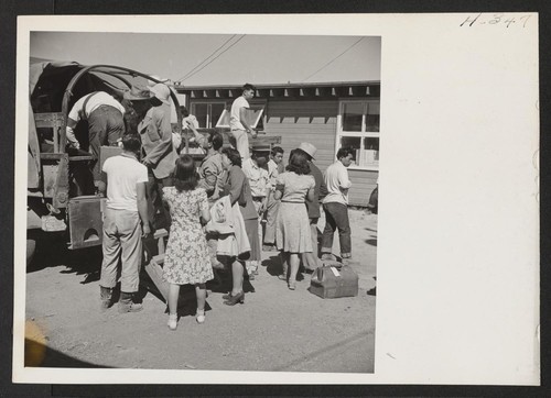 New arrivals from the Jerome Center, having passed through the induction routine, are shown boarding trucks which will take them to a mess hall and later to their new quarters. Photographer: Mace, Charles E. Newell, California