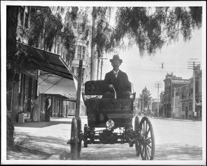 A man driving a topless automobile on Spring Street looking north from 8th, ca.1900