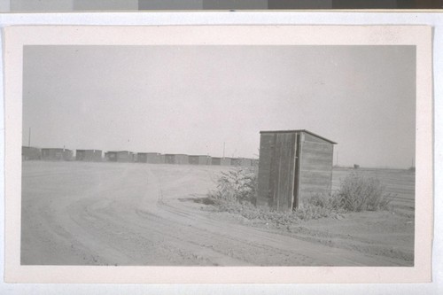 July, 1936, Kern County, Kern Lake District. Frick Ranch. Ladies' privy. Note weeds growing around the building and necessity of crossing freshly ploughed ground to reach the building