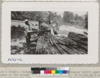 Pictures of the Jackson Tree Harvester outfit sawing lumber at the George Volz place in Eldorado County. It is run by 3 men who accompany the outfit plus 1 or 2 men furnished by the land owner. The charge for the machine and the 3 men is $18.00 per thousand to the farmer. Mr. Volz was having a number of rather large logs sawed into the tree props for the orchard and framing lumber. The logs had been left by a logger who cut timber on his place 2 years ago. August 1950. Metcalf