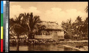 Thatched-roof home on the water, India, ca.1920-1940