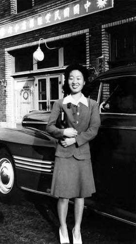 Photograph of a woman standing in front of a car and Kuo Min Tang