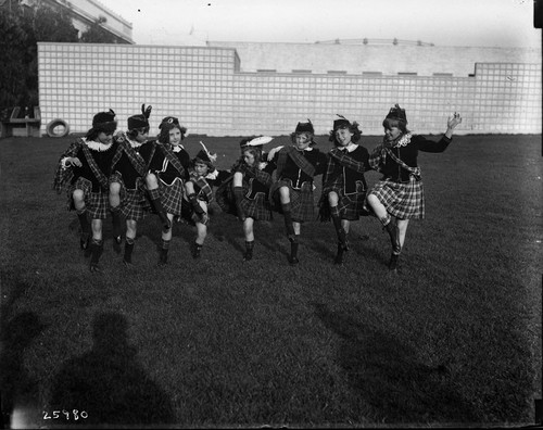 Eight girls kicking high in a Scottish dance