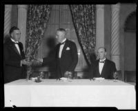 Realtor Clifford C.C. Tatum exchanging gavel with another man at real estate banquet, [1925-1930?]