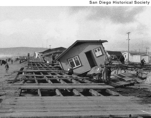 People examining houses in Ocean Beach that have been blown off their foundations
