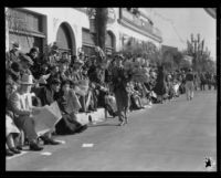 Street vendor selling souvenir canes with toy footballs attached at the Tournament of Roses Parade, Pasadena, 1932