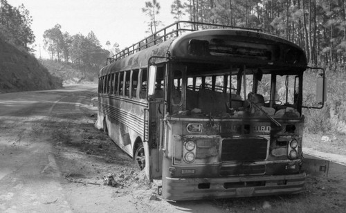 Burnt Blue Bird bus near a road, Guatemala, 1982