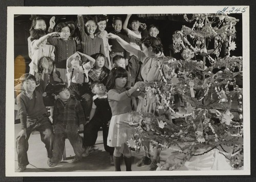 There aren't any Christmas trees for the barracks room homes of these children in a Relocation Center. A Granada merchant