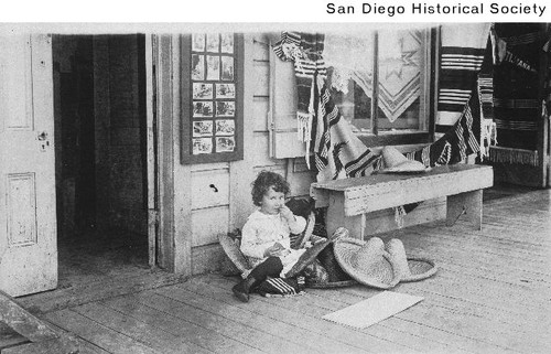 Roy Magruder, Jr. sitting near a doorway with sombreros and blankets