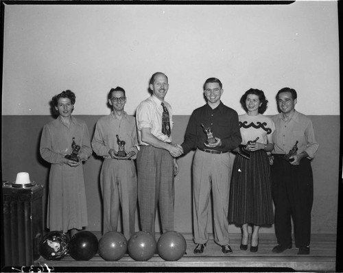 Three men and two women receiving bowling trophys
