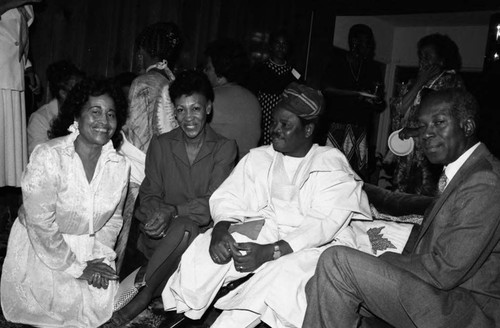 Maxine Waters sitting with a man in traditional clothing during a Black Women's Forum event, Los Angeles, 1982