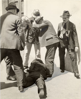 [Group of men standing over another man who was wounded during longshoremen's strike]