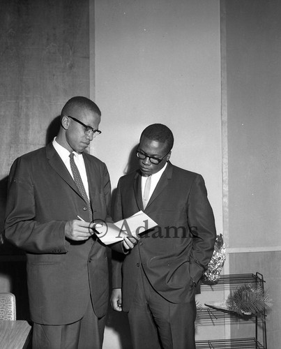 Malcolm X and John Shabazz examining a document, Los Angeles