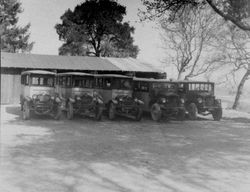 Fleet of five Analy Union High School buses lined up in front of a garage building, about 1925