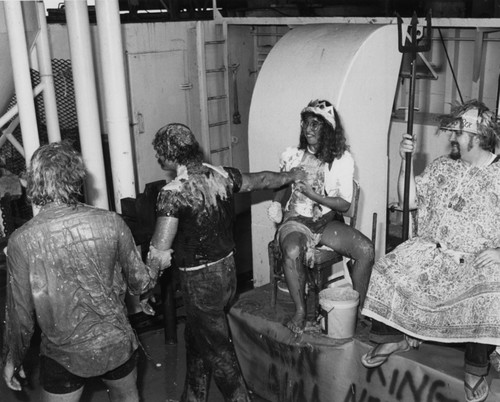 King Neptune and her highness Amphitrite initiating pollywogs (first time equator crossers) during a Crossing the Line ceremony aboard the D/V Glomar Challenger on one of the legs of the Deep Sea Drilling Project. 1983