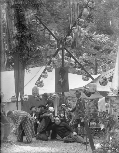 Men in camp with poster "Moulin Rouge," and paper lanterns, Bohemian Grove. [negative]