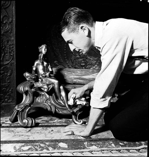 Attendant polishing andirons in the library of the Huntington residence