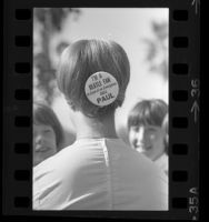 Girl with button pinned in her hair reading "I'm A Beatle Fan In Case of an Emergency Call Paul" in Los Angeles, Calif., 1964