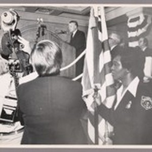 Audrey Haynes, customs patrolman, guards flay at right as cameras cover ...