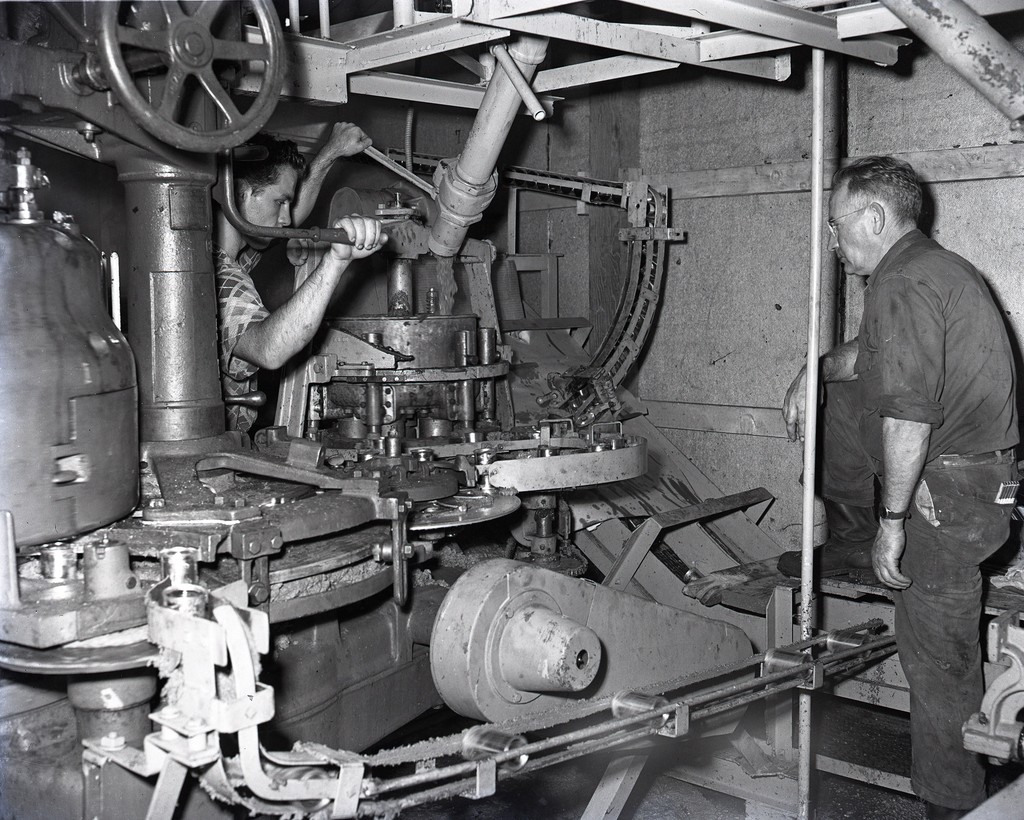 Two men operating a canning machine at the fish cannery, Newport Beach ...